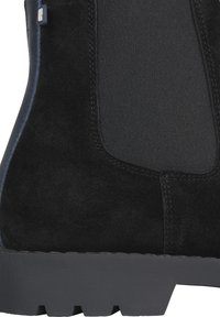 Botín de ante negro con un panel de elastano texturizado y una suela de goma negra resistente, caracterizado por un diseño limpio y acentos minimalistas.