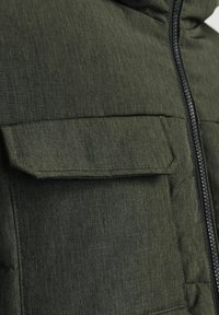 Olivgrüne gepolsterte Jacke mit texturiertem Finish, einem Frontreißverschluss und einer großen Klapptasche auf der Brust.