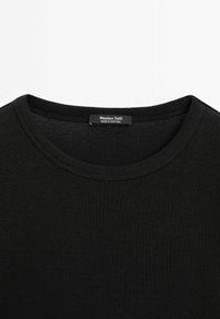 Nahaufnahme eines schwarzen Rundhalsshirts, das den gesteppten Halsrand und das Innenschild mit dem Markennamen "Massimo Dutti" und "Hergestellt in Portugal" zeigt.