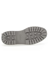 Gray rubber shoe sole with deep tread pattern, featuring angled and rectangular lugs for traction. Brand logo visible on the surface.