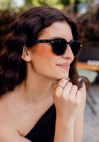 Černé a želvovinové sluneční brýle se čtvercovými čočkami, s pozlacenými akcenty a značkou "VUCH" po straně, nošené osobou.