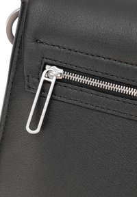 Czarna skórzana torebka z kieszenią na zamek błyskawiczny, wyposażoną w srebrny metalowy uchwyt oraz fakturowaną powierzchnią. Szwy widoczne są wzdłuż krawędzi.