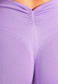 Leggings lavanda a vita alta con una texture a coste e una cucitura raccolta sul retro, che enfatizza una silhouette aderente.
