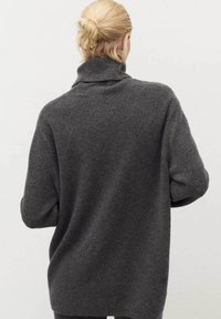 Gray, oversized turtleneck sweater made of soft wool, featuring ribbed texture at the collar and cuffs, with a relaxed silhouette.