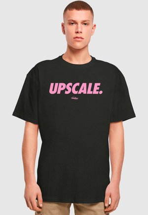 Black t-shirt featuring large pink text that reads "UPSCALE." It has a relaxed fit and casual design, suitable for various occasions.