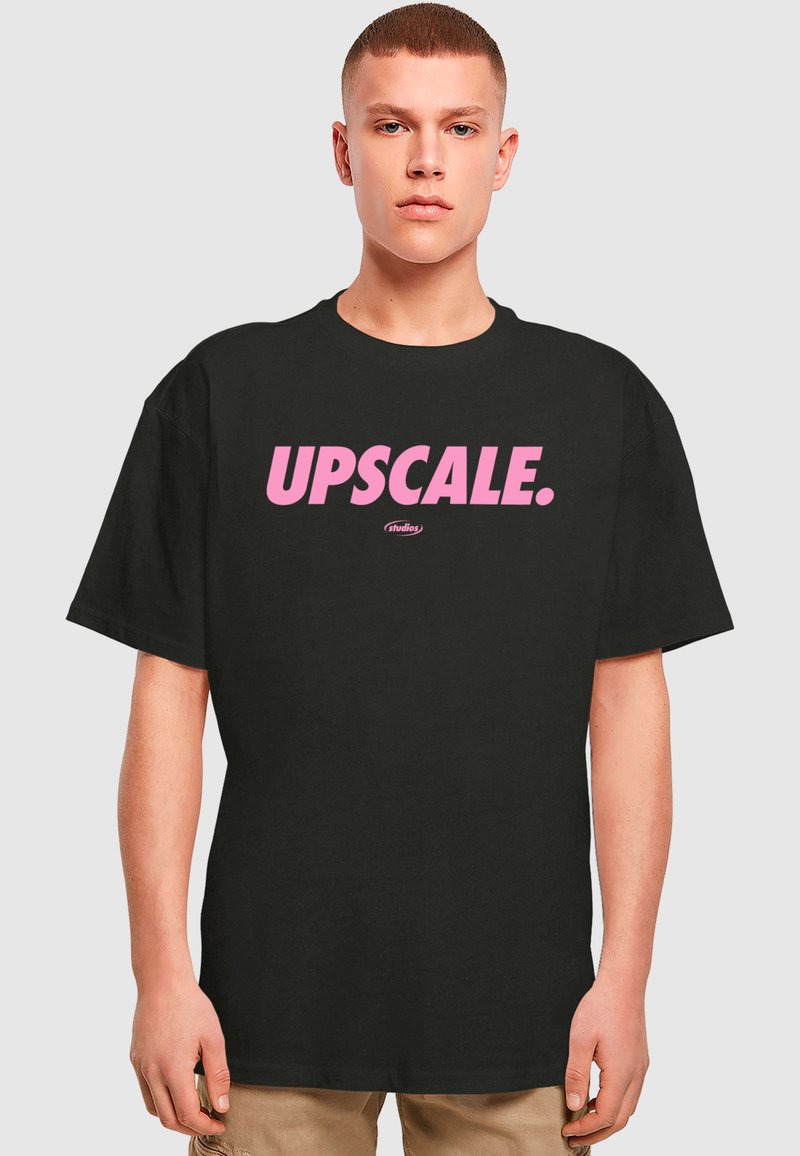 Sort T-shirt med stort pink tekst, der står "UPSCALE." Den har en afslappet pasform og et uformelt design, der passer til forskellige anledninger.