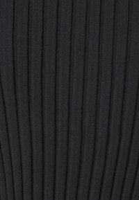 Svart ribbad textil med vertikala ränder, som visar en mjuk struktur med ett konsekvent mönster och en svag lyster från materialet.