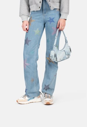 Light blue denim jeans featuring multicolored star embellishments, paired with a light blue handbag and neutral-toned sneakers.