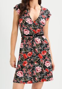Czarna sukienka w kwiaty z kopertowym fasonem i krótkimi rękawkami. Czerwono-różowe kwiatowe wzory, dopasowana talia z paskiem. Gładka tekstura.
