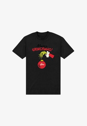 Camiseta negra con una mano verde del Grinch sosteniendo un adorno navideño rojo etiquetado como "El Grinch" y texto encima que dice "¡Feliz GRINCHMAS!"