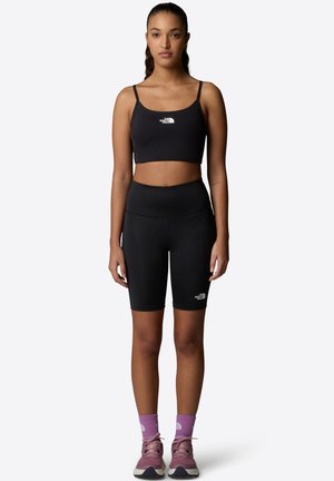 Black sports bra and matching bike shorts made from stretchy fabric. Notable details include a small logo on the left hip and functional design.