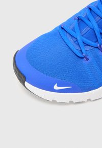 Blå atletiksko med en tekstureret mesh-overdel, hvid sål og Nike-logo. Har letvægtsmaterialer og et fremtrædende snøresystem.
