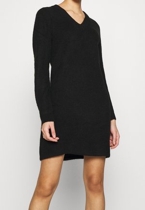 Black knitted dress with a V-neck, long sleeves, and a relaxed fit. Features a hem that falls above the knees and a textured fabric.