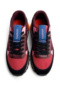 Zapatillas de color marrón y rosa con una parte superior de malla texturizada, cordones negros, una etiqueta de logo azul y un interior naranja. Suela curvada con detalles en negro.