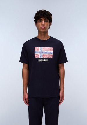 T-shirt marine à manches courtes avec un graphisme prominent du drapeau islandais en rouge, blanc et bleu ; texte de marque en dessous du design.