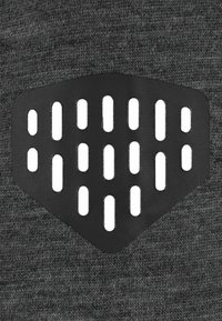 Black textured material with vertical and horizontal cutouts, shaped like a shield, attached to a gray knit fabric background.