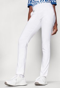 White, fitted pants made of lightweight material with a smooth texture, featuring a discreet pocket and contrast stitching.