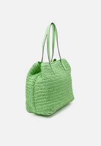 Světle zelená tkaná taška s texturovaným pleteným vzorem a dvěma dlouhými ramenními popruhy na bílém pozadí.