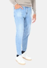 Jeans in denim azzurro chiaro con una vestibilità rilassata, design a cinque tasche e leggera scoloritura. Abbinati a sneakers bianche.