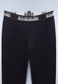 Czarne legginsy z szerokim czarnym pasem w talii, z powtarzającymi się białymi logo Napapijri i centralnym pionowym szwem.