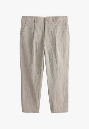 Lyse beige bukser med nålestriber, sidelommer, bæltestropper og knaplukning foran, vist fladt mod en hvid baggrund.