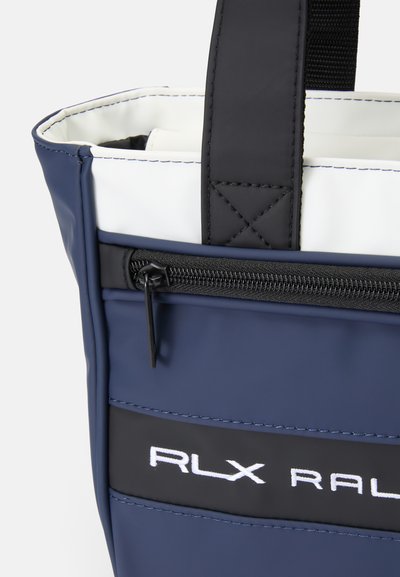 Saco impermeável em azul-marinho com forro branco, apresentando um bolso com fecho preto e costuras em contraste; possui alças pretas robustas para fácil transporte.