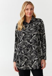 Blusa a maniche lunghe in tessuto nero con motivo a foglia di palma bianca. Design con colletto e chiusura a bottoni, vestibilità morbida.