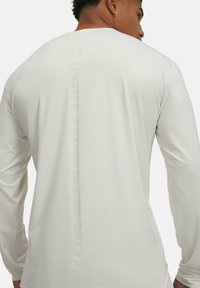 Maglia sportiva a maniche lunghe bianca con una discreta scritta in rilievo "UNDER ARMOUR RUNNING" sul retro. Tessuto morbido e flessibile con una finitura liscia.