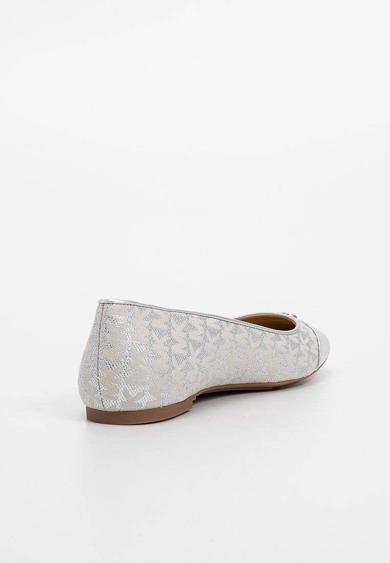 Chaussure plate argentée avec motif géométrique texturé, bout fermé et semelle marron, présentée à un léger angle sur fond blanc.