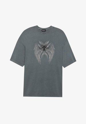 Sivá oversized tričko s krátkymi rukávmi, s centrálnym potlačou podrobných krídel v čierno-bielej farbe a jemnou textúrou.