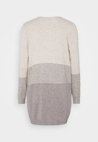 Långärmad stickad tröja i ljusbeige och grå färgblockdesign. Mjuk textur med ribbade ärmslut och rundad söm. Vyn bakifrån visas.