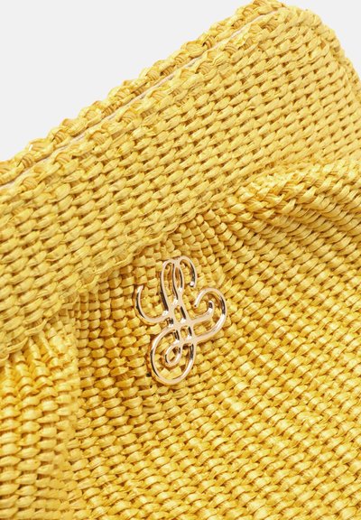 Pochette en tissu tissé jaune avec un détail froncé et un petit emblème métallique décoratif doré à l'avant.