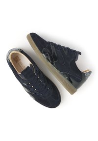 Ein Paar dunkelblaue Wildleder- und Lackledersneaker mit Gummisohlen, schwarzen Schnürsenkeln und gemusterten Akzenten an der Ferse, von oben und von der Seite gezeigt.