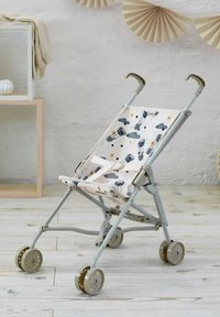 Carrozzina leggera per bambini con tessuto beige stampato con mongolfiere e nuvole, telaio in metallo e ruote doppie in plastica su pavimento in legno.