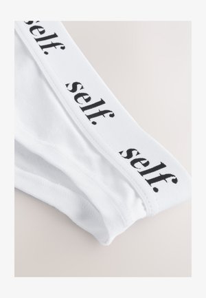 Hvide bomuldsunderbukser med en sort elastisk talje, hvor "self." er trykt med små bogstaver. Glat tekstur, klassisk design.