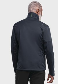 Dark blue zip-up jacket featuring a high collar, textured fabric, and a green accent stitch along the back. Smooth fit and athletic design.
