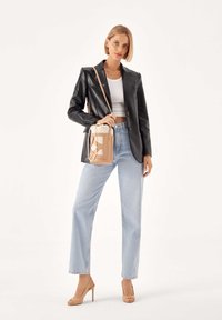 Czarna skórzana marynarka, biały krótki top, jasnoniebieskie dżinsy z wysokim stanem, beżowa torebka z geometrycznymi akcentami oraz cieliste szpilki.