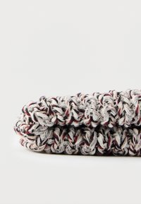 Produs textil tricotat, cu o suprafață texturată și un model multicolor de fire albe, negre și roșii, având o formă cilindrică.