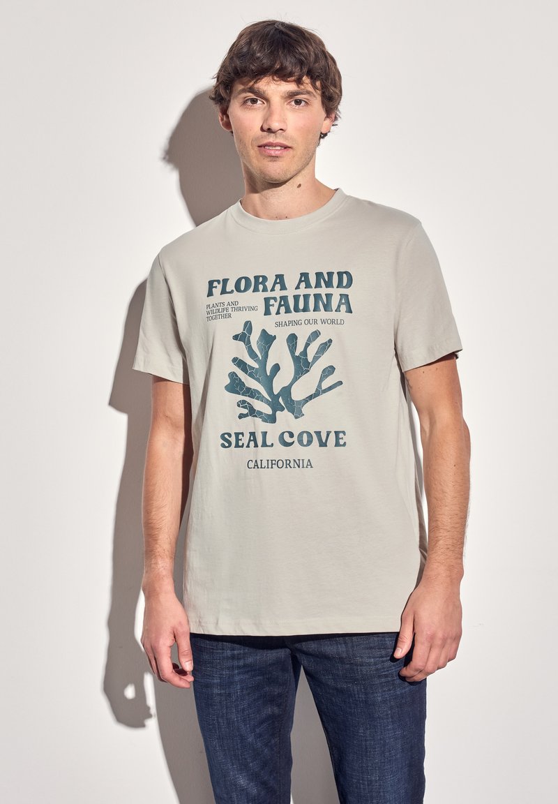 Vaaleanharmaa t-paita, jossa on sininen koralligrafiikka ja teksti "Flora and Fauna Seal Cove California". Lyhyet hihat, pyöreä pääntie.