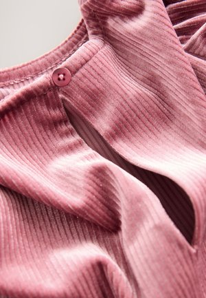 Tessuto rosa a coste con una leggera lucentezza, caratterizzato da una chiusura con bottoni e una texture morbida, che mette in risalto pieghe profonde e drappeggi.