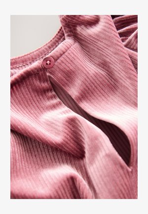 Tissu rose côtelé avec une légère brillance, doté d'une fermeture à boutons et d'une texture douce, mettant en valeur des plis et des drapés profonds.