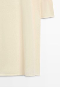 T-shirt écru à manches courtes avec un ourlet droit, présenté sur un fond blanc uni.