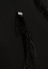 Top in tessuto nero con lunghi dettagli in frange nere e un particolare rettangolare in strass trasparenti. Texture liscia con un design aderente.