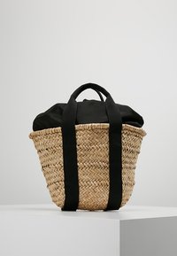 Borsa a tracolla in paglia intrecciata con manici in tessuto nero e chiusura superiore in tessuto nero, esposta su un piedistallo bianco contro uno sfondo grigio.