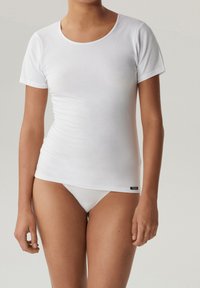 Biały bawełniany t-shirt z krótkim rękawem i okrągłym dekoltem, charakteryzujący się dopasowanym krojem i delikatnym streczem. Metka widoczna na dole.