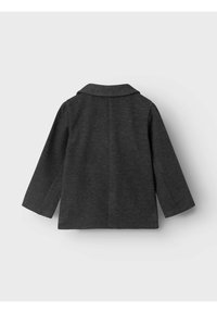 Cappotto grigio, texturizzato, con colletto, maniche lunghe e silhouette dritta. Cuciture nascoste e dettagli minimi esaltano il suo design elegante.