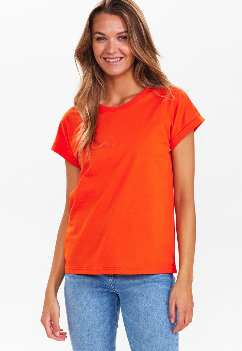 T-shirt di cotone arancione brillante con maniche corte e scollatura rotonda, caratterizzata da una vestibilità comoda e una texture liscia. Abbinata a jeans blu.