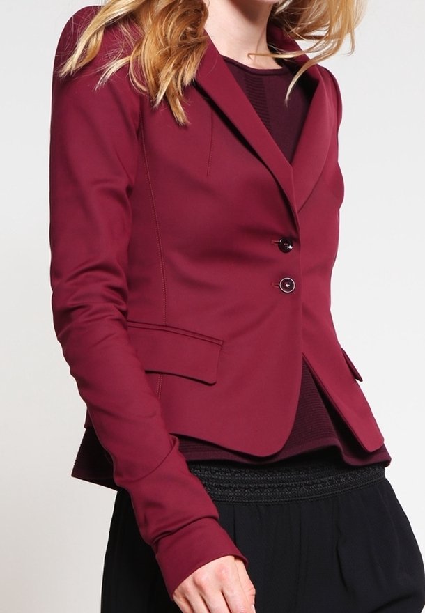 Blazer burdeos con un diseño ajustado, cierre de un botón y dos bolsillos delanteros. Fabricado en tejido suave con una silueta entallada.