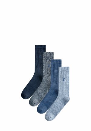 Four pairs of socks in blue tones. Varied textures include ribbed and smooth, with solid and mottled patterns. Each has a logo detail.