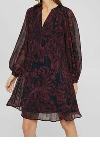 Långärmad bourgogny klänning med djup V-ringning, transparent tyg, blommönster och ett samlat midja, som flödar ner till en längd vid mitten av låret.